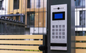 Access control keypad and video intercom installed beside a gated property entrance.
