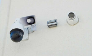 PTZ and fixed security cameras with an audio deterrent speaker and LED illuminators mounted on a building exterior.