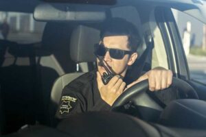 OnView security officer driving a patrol vehicle and communicating by radio with a monitoring agent.